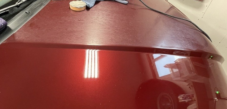 Paint correction 50/50 on a red hood, dull above the crease line and corrected below