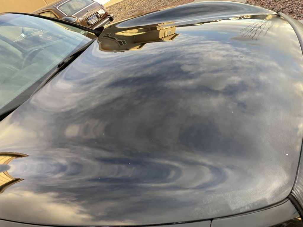 The same hood after paint correction, reflecting sky and clouds