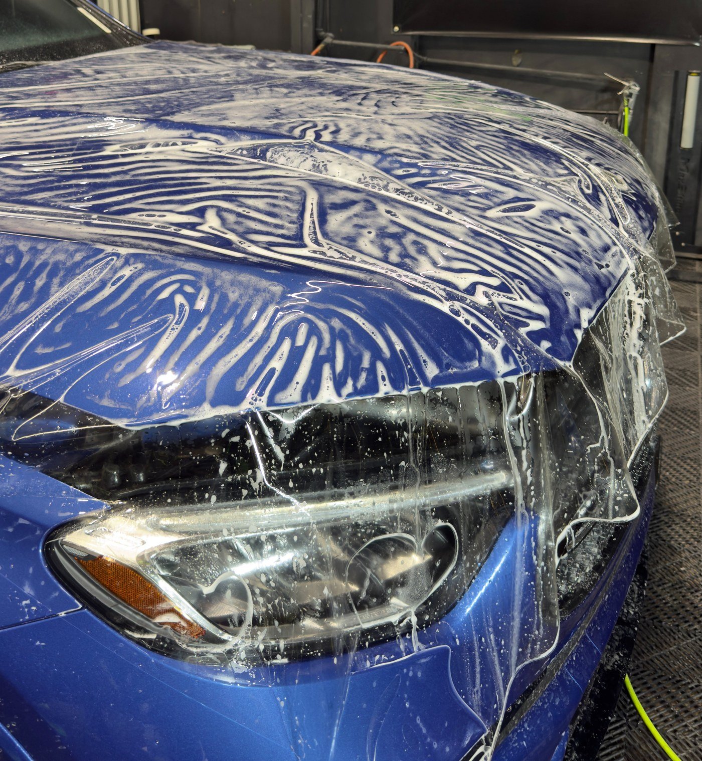 Paint protection film laid on a hood, still wrinkled over the slip solution before it is squeegeed flat